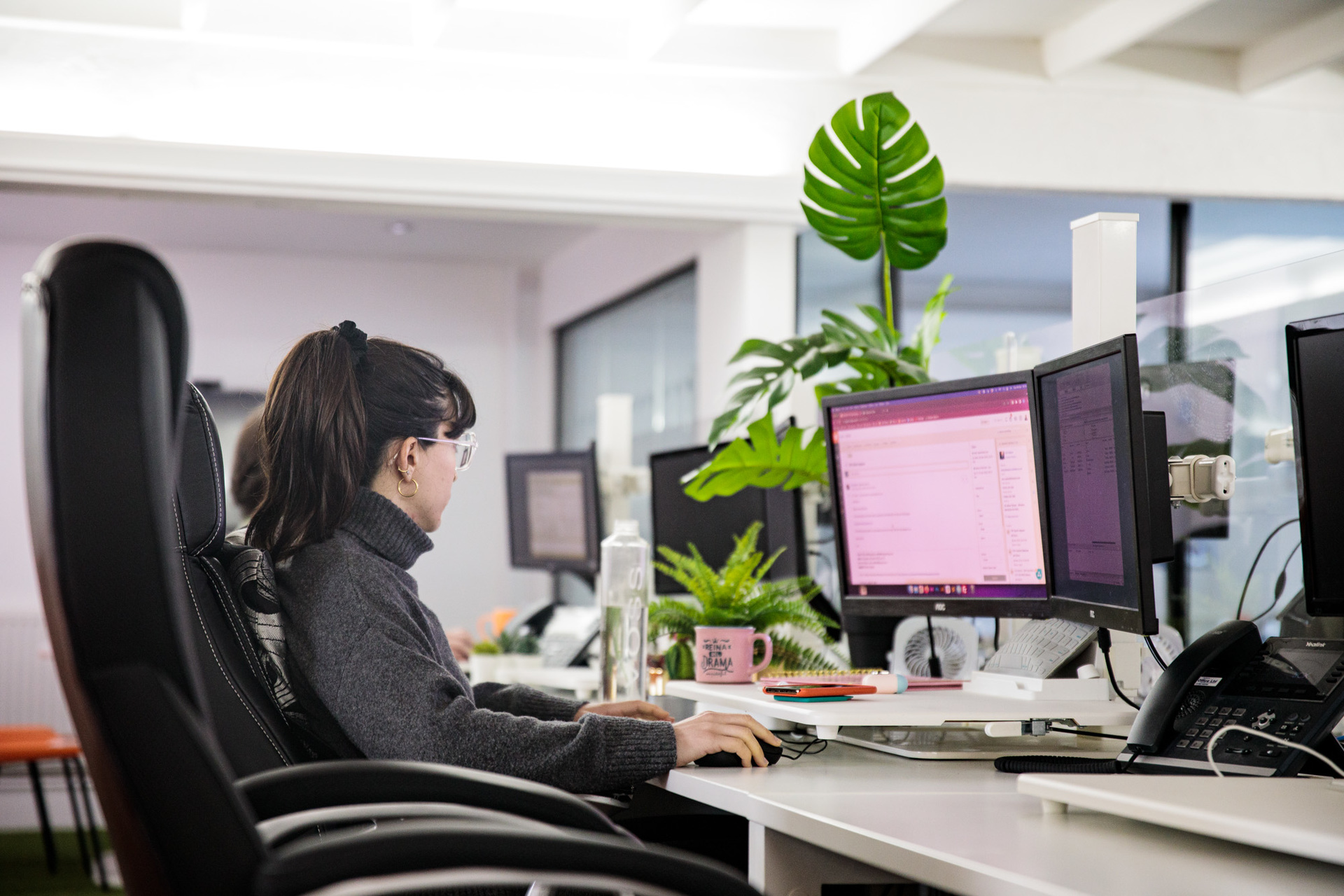 A woman web designer sat at her desk working on her desktop computer